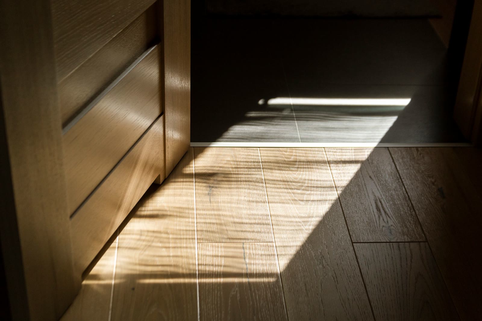 Luce del pomeriggio che disegna le ombre di una finestra su un parquet